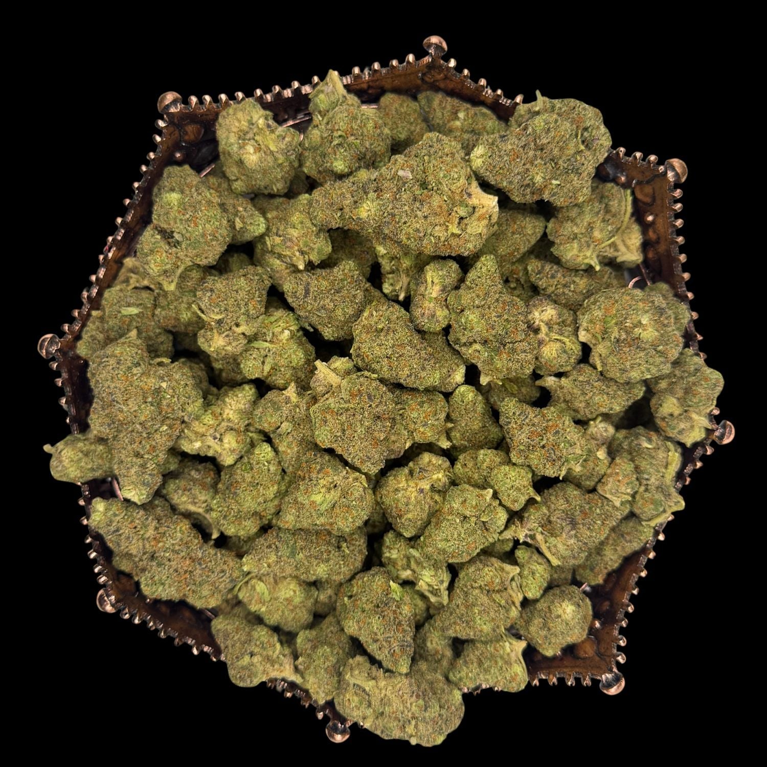 Dense indoor THCA flower buds in a hexagonal copper tray, photographed on black